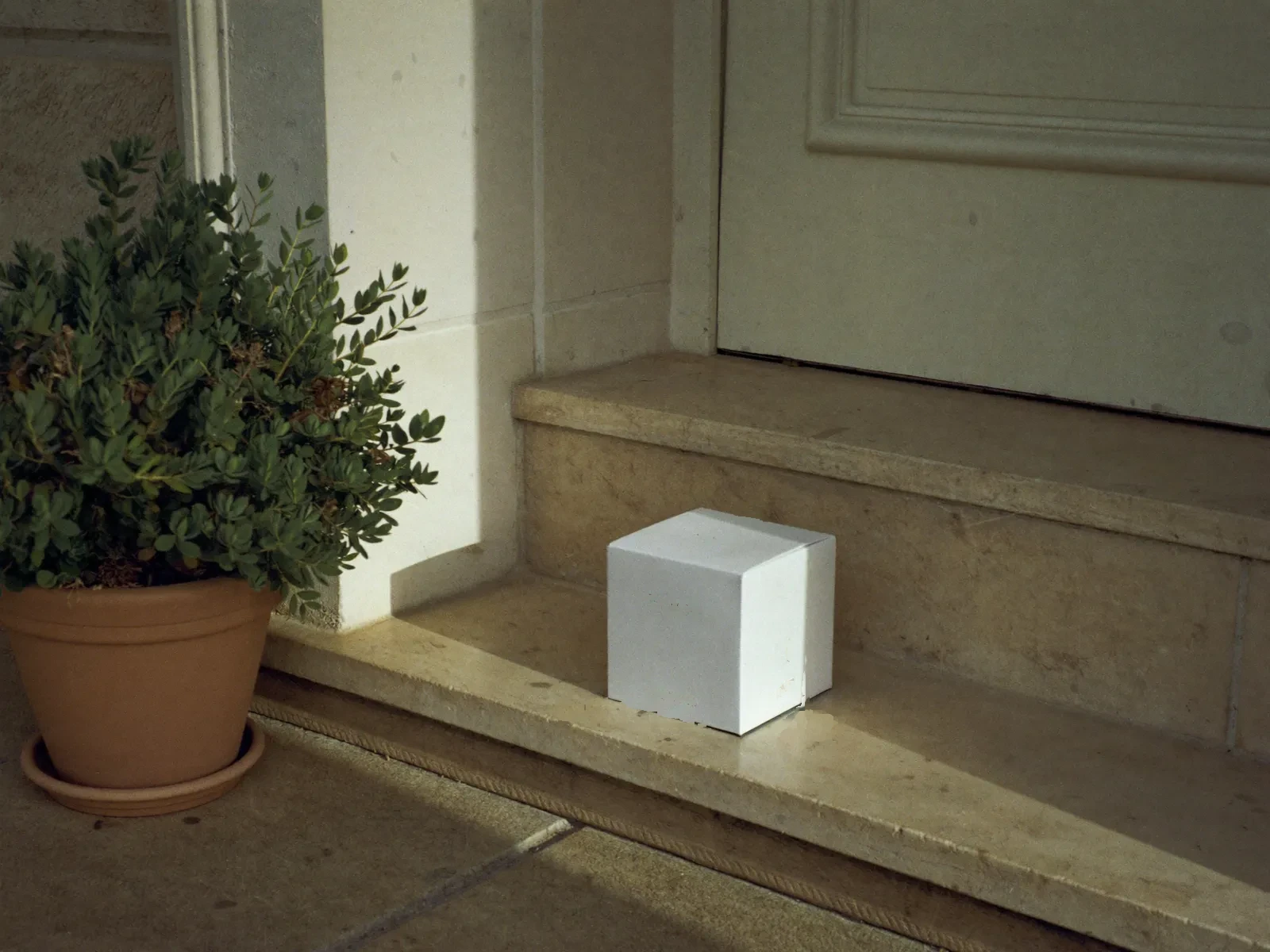 A plain unmarked parcel on a stone doorstep in morning light