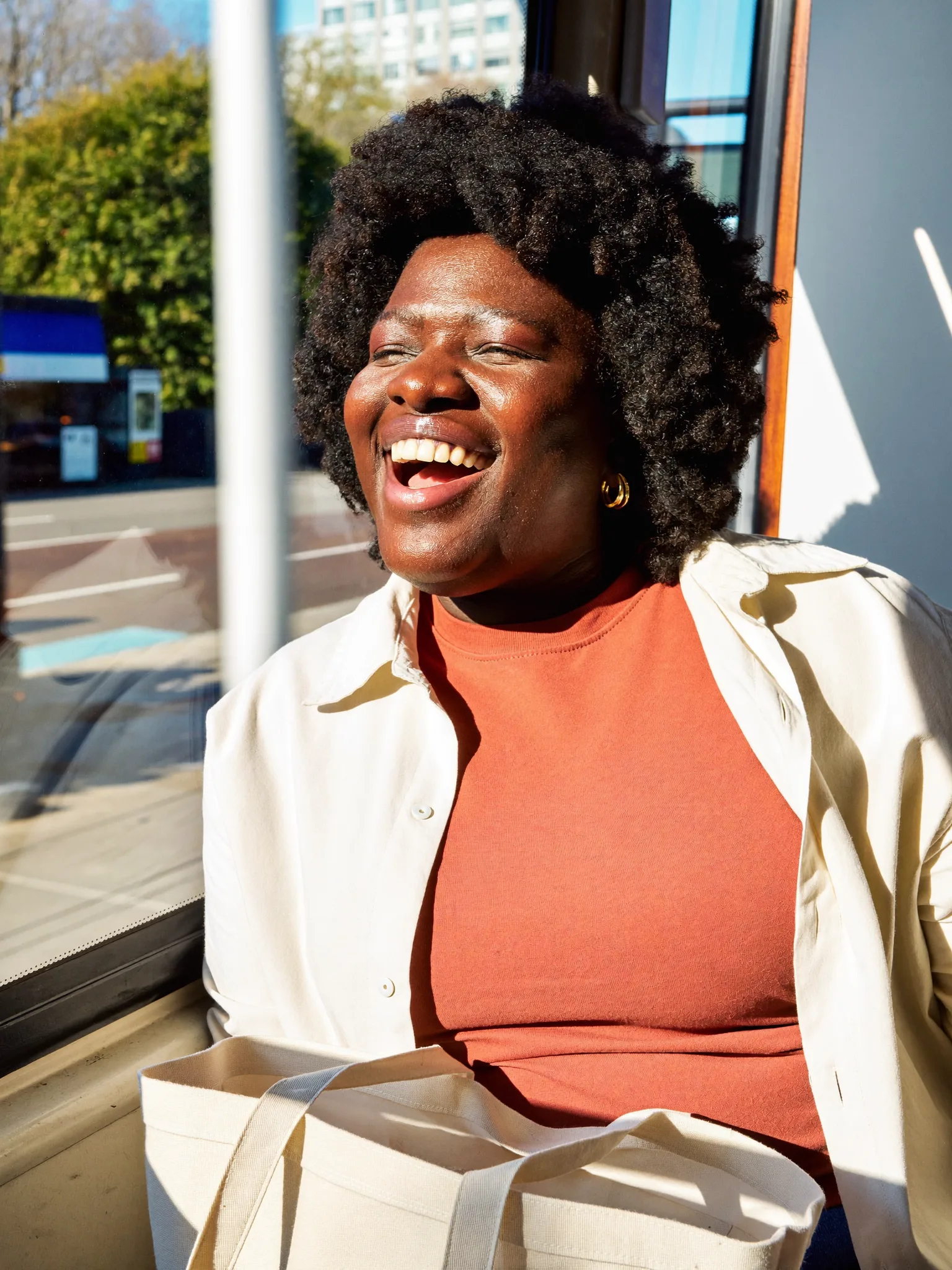A woman smiling in morning sunshine on her bus commute