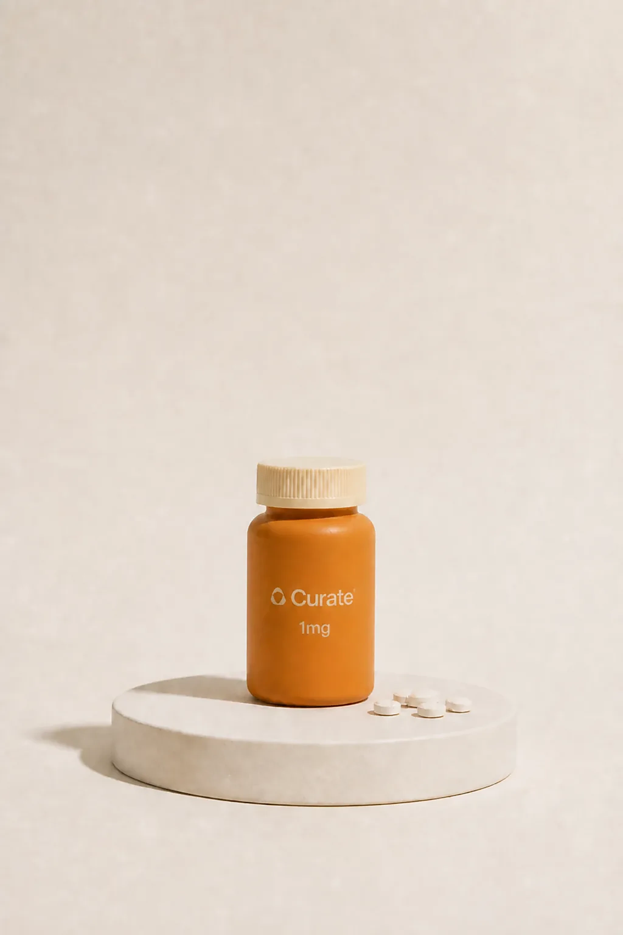A Curate pill bottle with loose white tablets on a studio plinth