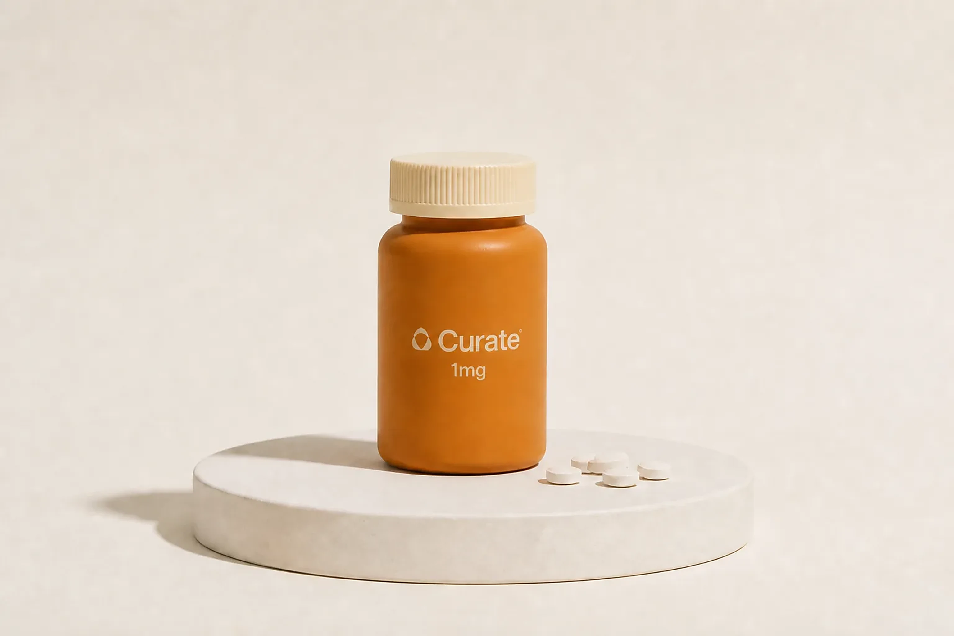 A Curate pill bottle with loose white tablets on a studio plinth