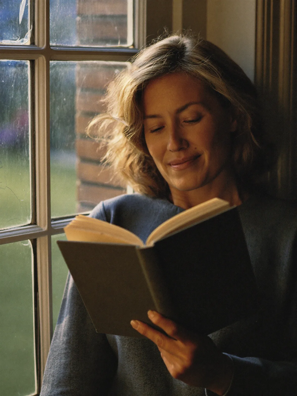 A woman reading by a bright window, unhurried