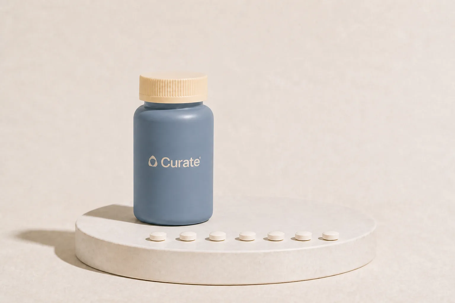 A slate-blue Curate pill bottle with seven tablets in a row, one for each day
