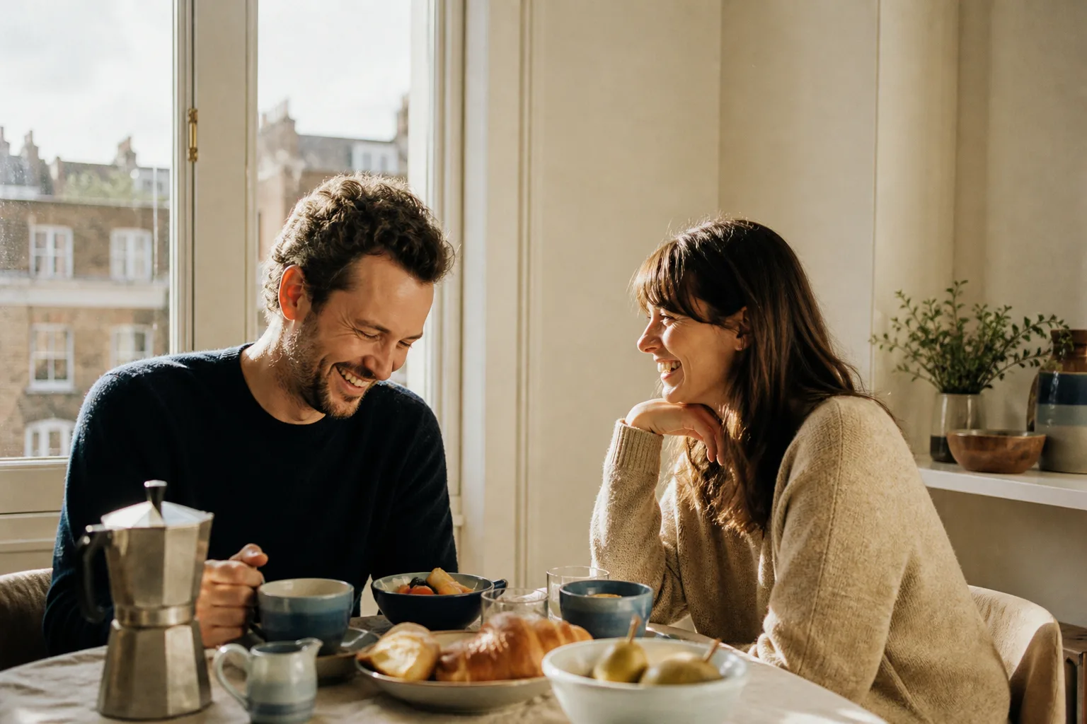 A couple laughing together over breakfast in warm morning light